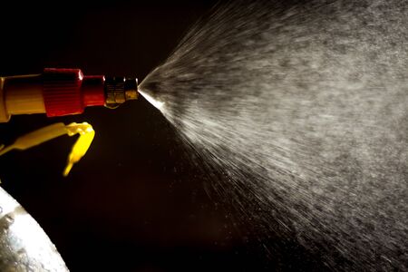Air pump water spray bottle. close up of a spraying water drops isolated on black background.の写真素材