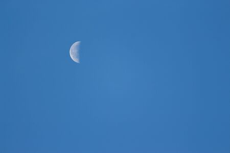 Moon Lunar / Luna on the blue sky. Half Lunar moon in a clear daylight sky. Earth Moon Lunar on day time with Copy space for text. Luna on the day sky. Selene .Cynthiaの写真素材