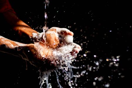 Washing hands.Man washing his hands isolated on black background.Corona virus pandemic prevention wash hands with soap warm water & rubbing nails & fingers washing frequently.Hygiene & Cleaning Hands.の写真素材