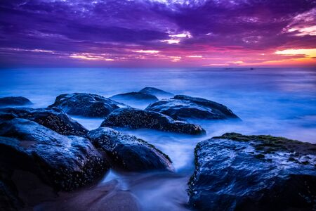 Beautiful sunrise over the beach in long exposure. Moving elements sunrise and wave photography from the rocky beach in india. Red sky in bay of bengal , slow-shutter Sea Waves and Rocks photography.の写真素材
