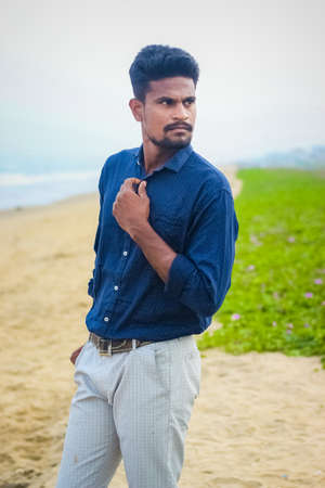 Sexy Indian model posing with wearing formal shirt & pant in sea beach view. Handsome and confident men. Outdoor portrait of smiling young Asian indian man on the beach.の写真素材