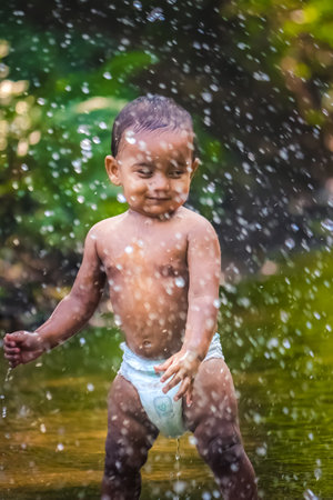 Little Cute Baby Boy Playing In River Water. Portrait of Boy Child Having Fun and Joy On a Forest River. Little Funny Boy Playing In Water. Baby Boy Stock Images.の写真素材