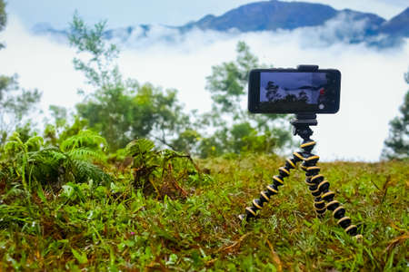 Smart Mobile phone holding on mini Tripod stand at beautiful landscape. Mobile tripod Stock images.の写真素材