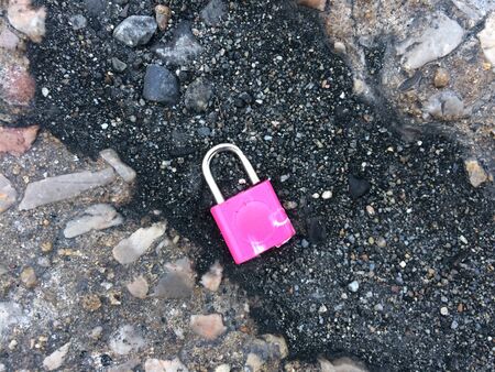Old pink padlock and cement floor.