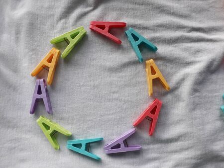 The green pink yellow  blue purple cloth clip placed on a white cloth.の写真素材