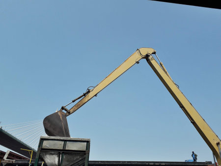 Large yellow scoop Are scooping the white Urea chemical fertilizer From a pontoon boat to unload