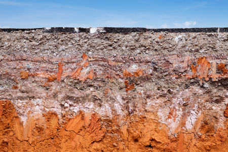 Layer of soil beneath the asphalt road with blue skyの写真素材