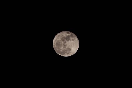 Full moon over dark black sky at nightの写真素材