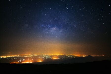 Milky way galaxy and city light at Phutabberk Phetchabun in Thailand.Long exposure photograph.With grainの写真素材
