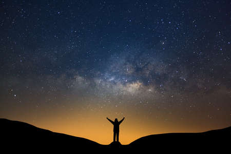 Milky way galaxy with stars and silhouette of a standing happy man, Long exposure photograph, with grain.の写真素材