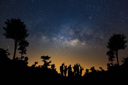 Landscape with milky way, Night sky with stars and silhouette of happy people standing in forest,...