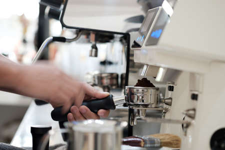 man holding portafilter loaded with grinded coffee and preparing fresh espressoの写真素材