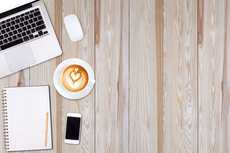 Top view laptop computer or notebook,mobile phone and cup of latte art coffee on wooden table. Business template mock up for adding your text.の写真素材