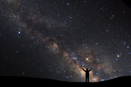 landscape with milky way, Night sky with stars and silhouette of a standing sporty man with raised up arms on high mountain.
の写真素材
