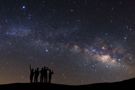 landscape with milky way, Night sky with stars and silhouette of a standing sporty man with raised up arms on high mountain.の写真素材
