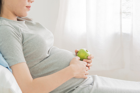 pregnant women and fruit  relax on bed in the room.の写真素材