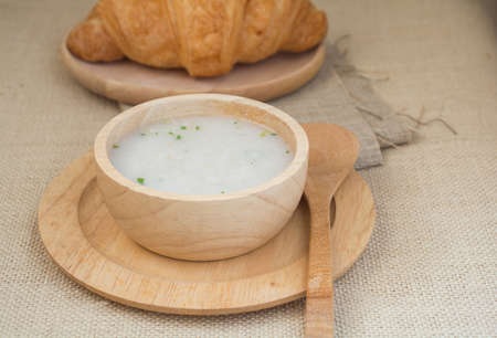 Rice soup in a wooden cup and spoon on the breakfast tableの写真素材