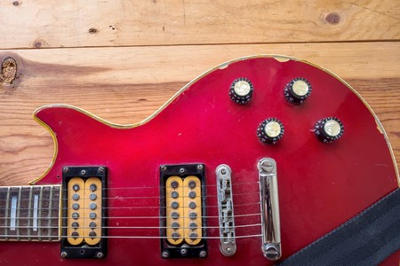 Vintage red guitar on old wood surface.
