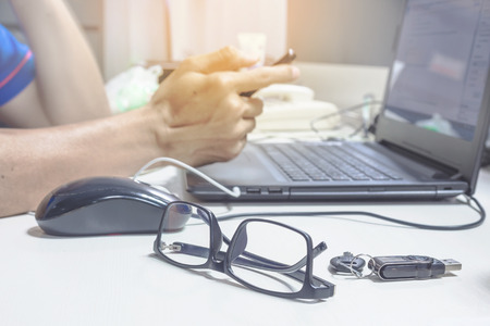 Side view shot of a man's hands using smart phone with notebook glasses and flash drive