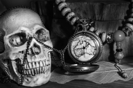 Still life photography pocket watch , bead necklace and blured human skulls in black adn whiteの写真素材