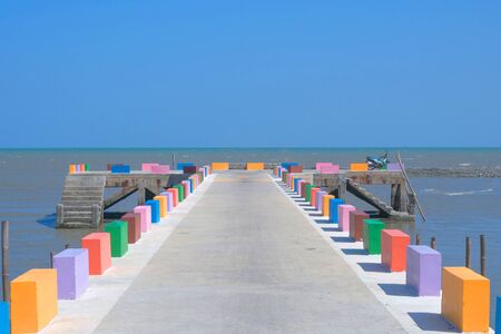 The cement bridge extends into the sea. With colorful barrier panels In the blue skyの写真素材