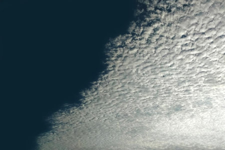 Blurred white clouds on a very dark blue sky.の写真素材