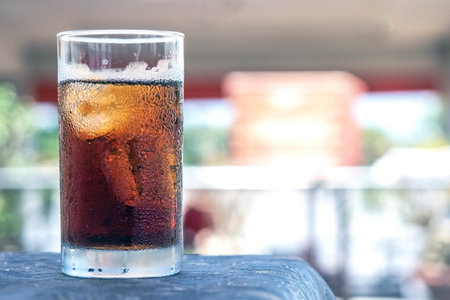 Glass of refreshing cola with ice on tableの写真素材