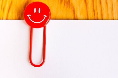 close up of a  red paper clip and white paper on wood tableの写真素材