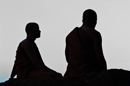 Silhouette of monk meditating at the top of the mountainの写真素材