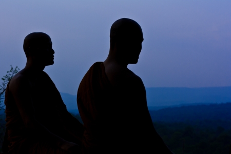 Silhouette of monk meditating at the top of the mountainの写真素材