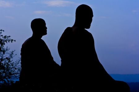 Silhouette of monk meditating at the top of the mountainの写真素材