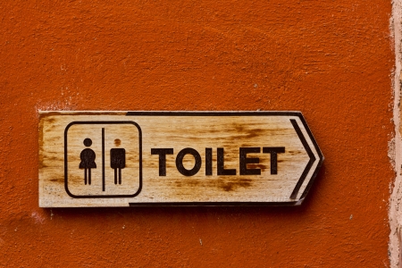 Ancient toilet sign on red concrete wallの写真素材