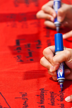Hand writing letters on red fabrics with blue penの写真素材