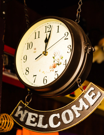 Hanging retro clock with welcome banner hangingの写真素材
