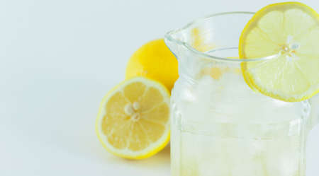 Lemon juice with ice in a glass jug Decorated with lemon slices With lemon cubes cut in half On a white backdropの写真素材