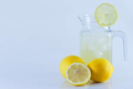 Lemon juice with ice in a glass jug Decorated with lemon slices With lemon cubes cut in half On a white backdropの写真素材