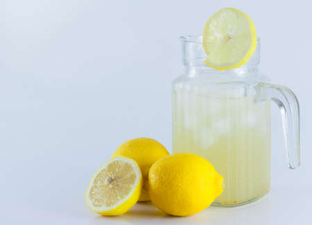 Lemon juice with ice in a glass jug Decorated with lemon slices With lemon cubes cut in half On a white backdropの写真素材