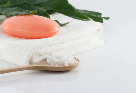 Bar soap on clean white towels, green leaves and salt scrub on white scenes for hygiene.の写真素材