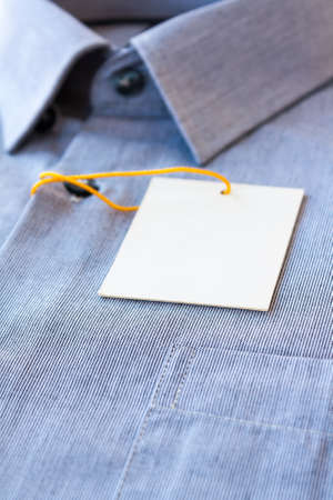 Small gray stripes men's shirt with a price tag and yellow-orange tag lanyardの写真素材