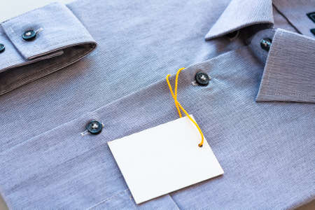 Small gray stripes men's shirt with a price tag and yellow-orange tag lanyardの写真素材