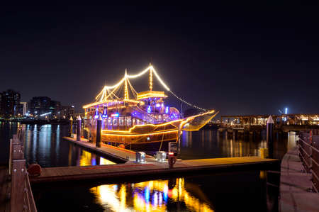 DEC 17, 2020, DUBAI ,UAE. Beautifully illuminated Dhow cruise dinner ship showing reflections on water captured at the Al seef village , Dubai, UAE.のeditorial素材