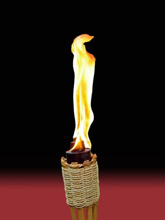 tiki torch with brilliant flame on black and red backgroundの写真素材