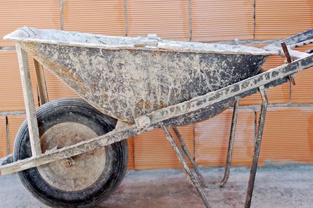 close up of well used wheelbarrow against a brick wallの写真素材