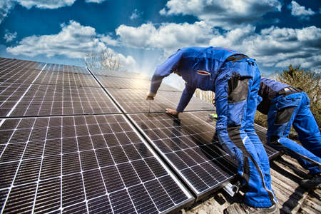 Worker installing solar photovoltaic panels on the roof of a houseの写真素材