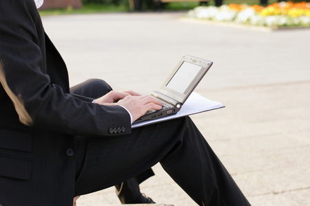 Cropped image of businessman working on computer and working paperwork outside in parkの写真素材