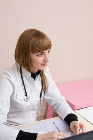 Smiling female doctor sitting at the table and writingの写真素材