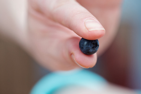 fingers holding a blueberryの写真素材