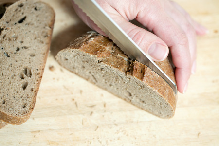 Hands cutting rye bread