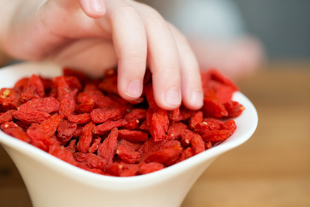 A childs hand taking dried goji berriesの写真素材