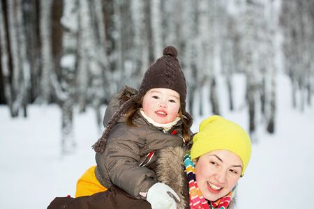 A mother holding her little girl on her backの写真素材